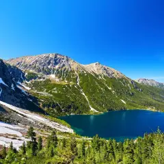 Górskie jezioro Morskie Oko otoczone zielonymi lasami i skalistymi szczytami Tatr.