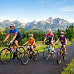 Rodzina na rowerach przemierza malownicze trasy rowerowe dla dzieci, podziwiając górskie krajobrazy.