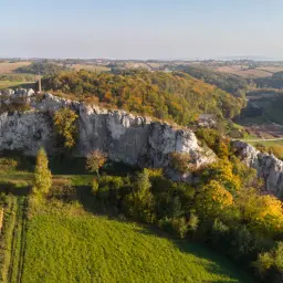 Skały wapienne na Jurze Krakowskiej w jesiennej szacie. W oddali pola i lasy.