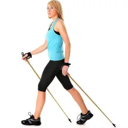 Kobieta w sportowym stroju ćwiczy nordic walking, trzymając kije.