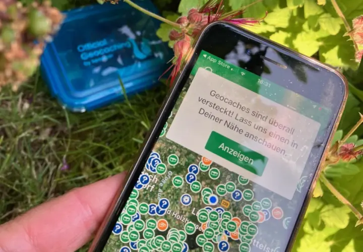 Smartfon pokazuje mapę z ukrytymi skarbami. To właśnie geocaching – zabawa w poszukiwanie skrytek z pomocą GPS.