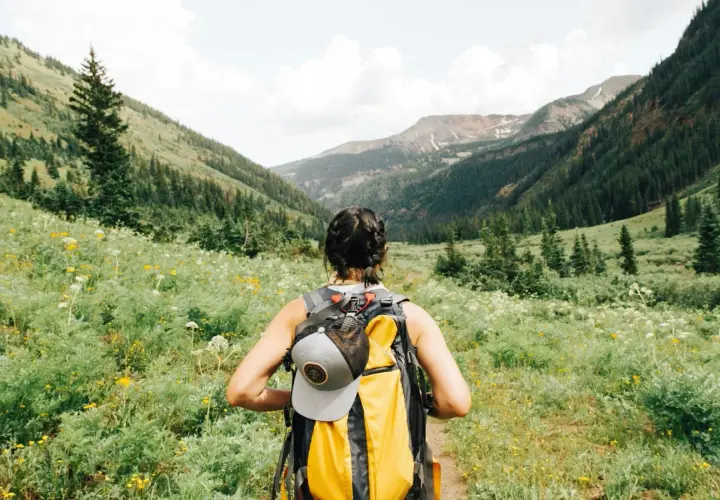 Kobieta z plecakiem wyrusza na szlak. To idealny dzień na trekking, który odróżnia się od zwykłego hikingu.