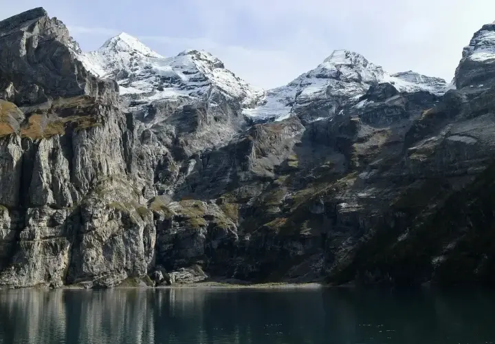 Majestatyczne Tatry w maju, z ośnieżonymi szczytami odbijającymi się w spokojnej tafli jeziora.