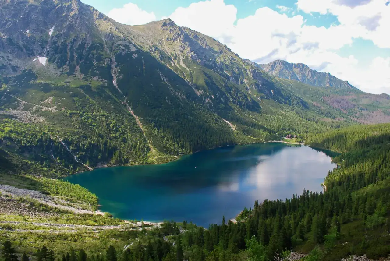Gdzie jest Morskie Oko? Jezioro otoczone górami i lasem, z wodospadem spływającym po zboczu.
